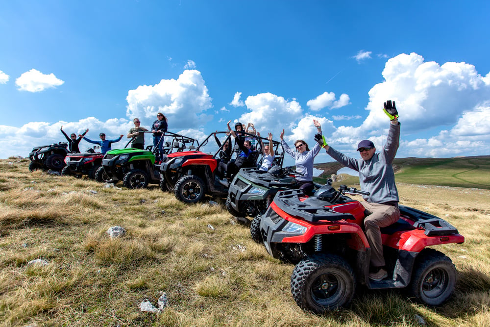 Friends driving off-road with quad bike or ATV and UTV vehicles